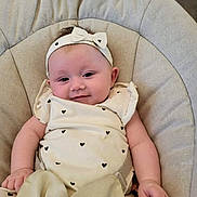 Paisley joined the competition — help win amazing prizes! baby, infant, smile, headband, bow, heart_pattern, white_clothing, cushion, chair, seated, cute, portrait, indoor, soft_fabric, baby_clothes, child, person, happy, comfortable, closeup