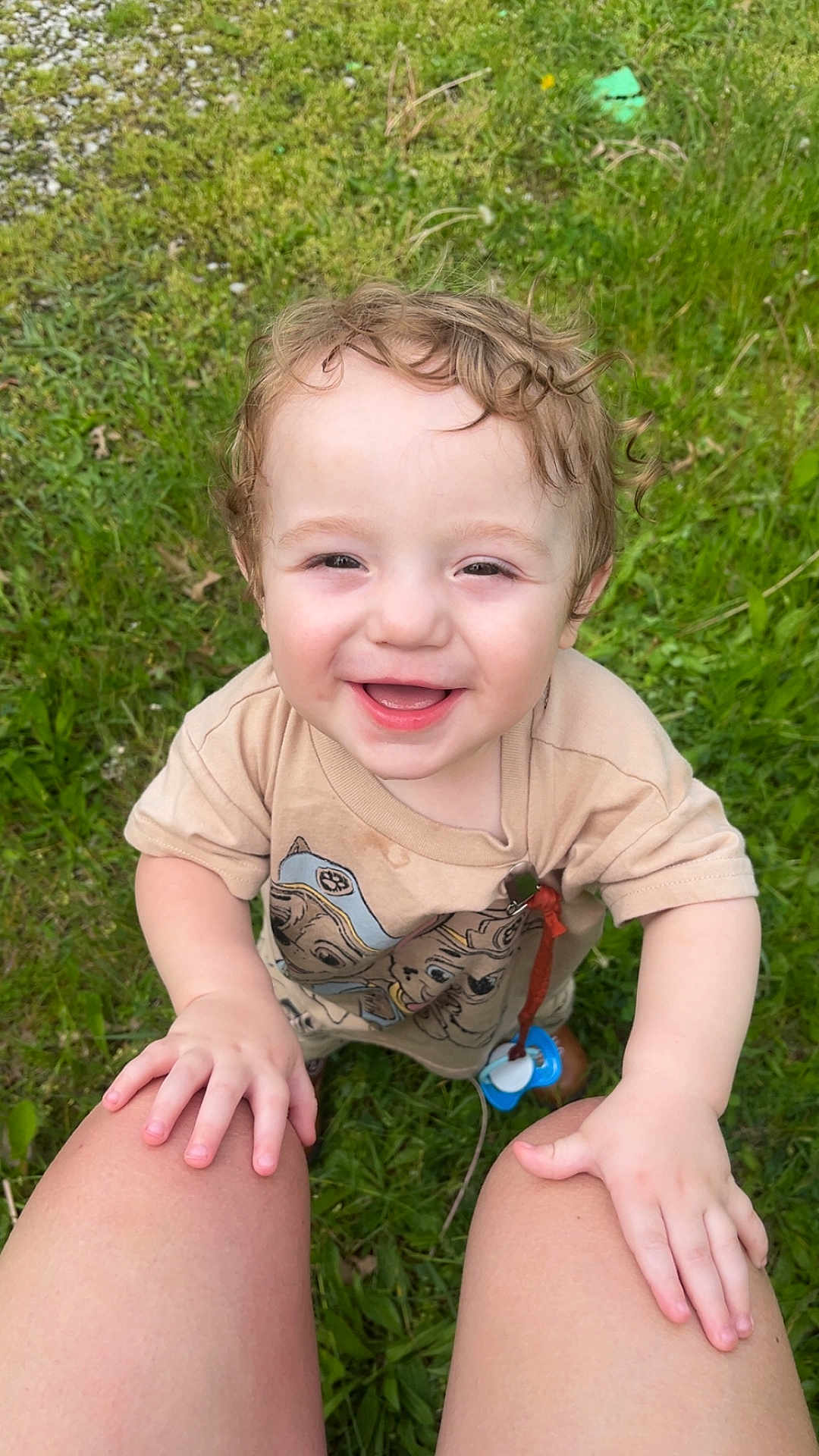 Alden is registered to the contest to win money with this photo: toddler, child, smiling, curly_hair, grass, outdoor, happy, baby, person, nature, greenery, clothing, pacifier, hands, legs, casual, cute, playing, summer, daylight