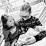 Lily joined the competition — help win amazing prizes! child, baby, newborn, hospital, bed, blanket, glasses, sweater, grinch, smile, family, indoor, person, holding, happy, together, monochrome, portrait, love, care