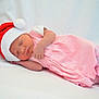 newborn, baby, sleeping, pink_clothing, santa_hat, infant, cute, holiday, soft, white_background, peaceful, portrait, lying_down, child, small, adorable, warm, resting, face, cozy