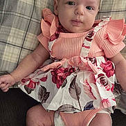 Aurora is registered to the contest to win money with this photo: baby, infant, child, plaid_blanket, pink_clothing, floral_pattern, diaper, lying_down, cute, face, legs, arm, indoor, soft_fabric, comfortable, skin, expression, person, newborn, casual
