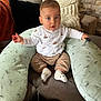 baby, child, infant, cushion, sofa, pillow, face, clothing, socks, indoor, seated, curious, expression, home, cozy, furniture, wall, texture, person, casual