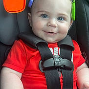 Jackson is registered to the contest to win money with this photo: baby, child, car_seat, safety_harness, red_shirt, smile, blue_eyes, toy, colorful, infant, cute, happy, seatbelt, closeup, face, skin, hand, indoors, child_safety, person