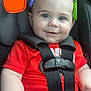 baby, child, car_seat, safety_harness, red_shirt, smile, blue_eyes, toy, colorful, infant, cute, happy, seatbelt, closeup, face, skin, hand, indoors, child_safety, person