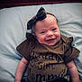 baby, smiling, infant, headband, bow, clothing, pillow, bed, wooden_headboard, cute, happy, portrait, lying_down, child, toddler, apparel, fabric, face, skin, indoors