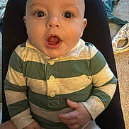 Rian is registered to the contest to win money with this photo: baby, infant, child, onesie, striped_clothing, sitting, legs, hands, face, eyes, mouth, surprised_expression, carpet, blanket, floor, indoors, furniture, lap, portrait, cute