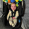 Addie joined the competition — help win amazing prizes! baby, car_seat, toy, smile, pajamas, infant, child, seatbelt, black, yellow, orange, blue, green, indoor, carpet, blanket, happy, cute, playful, comfortable