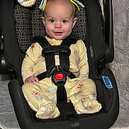 Addie joined the competition — help win amazing prizes! baby, car_seat, yellow_onesie, infant, toy, smile, straps, black_car_seat, face, child, indoor, floor, blanket, patterned_clothing, playful, happy, seated, cute, closeup, child_safety