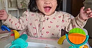 Mariana is registered to the contest to win money with this photo: toddler, baby_walker, smiling, happy, indoors, toy, child, person, face, playful, hair, kitchen, cabinet, furniture, floor, clothing, sleepsuit, expression, joy, home