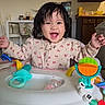 toddler, baby_walker, smiling, happy, indoors, toy, child, person, face, playful, hair, kitchen, cabinet, furniture, floor, clothing, sleepsuit, expression, joy, home