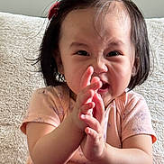 Mariana is registered to the contest to win money with this photo: toddler, child, clapping, pink_clothing, hair_clip, short_hair, indoors, cozy, expression, face, person, cute, baby, portrait, sitting, hands, young_child, happy, home, casual