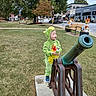 Grady joined the competition — help win amazing prizes! toddler, child, costume, dinosaur_costume, cannon, park, grass, bench, toy, autumn, tree, sidewalk, street, car, building, window, person, outdoor, curious, playful