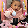 baby, child, car_seat, pink_clothing, plush_toy, toy, infant, face, hand, earrings, seatbelt, blanket, indoor, cute, portrait, holding, playing, soft_toys, young_child, expression