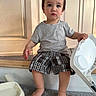 toddler, child, baby, portrait, sitting, high_chair, pouting, wide_eyed, short_hair, striped_shirt, plaid_shorts, barefoot, indoor, wood_paneling, carpet, furniture, chair, tray, close_up, natural_light
