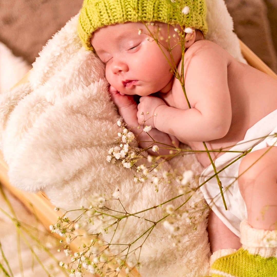 Korrin is registered to the contest to win money with this photo: baby, beanie, bed, blanket, bonnet, cap, clothing, face, flower, flowerarrangement, furniture, glove, hat, head, newborn, person, photography, plant, portrait, sleeping