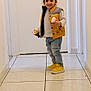 child, toddler, indoor, hallway, smiling, yellow_vest, yellow_shoes, jeans, toy_blocks, white_wall, tile_floor, long_hair, casual_clothing, standing, happy, person, footwear, door, playful, cute