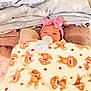 baby, bed, blanket, bottle, bow, cozy, face, feeding, hello_kitty_blanket, infant, newborn, patterned_blanket, pillow, pink_headband, plush, portrait, sleepy, soft_texture, swaddled, teddy_bear_pattern