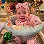 baby, infant, pink_clothing, headband, hello_kitty, baby_seat, christmas_tree, ornaments, holiday_decor, carpet, smiling, happy, indoors, festive, cute, child, person, portrait, seasonal, celebration