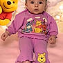 Tessa joined the competition — help win amazing prizes! animated_character, baby, bare_feet, cartoon_character, child, clothing, curious, cute, face, indoor, infant, pink_background, playful, portrait, purple_clothing, sitting, smiling_character, soft_texture, toy, winnie_the_pooh