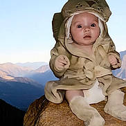 Tesssa is registered to the contest to win money with this photo: baby, child, costume, animal_costume, rock, mountains, outdoor, nature, landscape, sky, cute, portrait, infant, sitting, expression, face, clothing, scenery, daylight, young