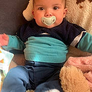 Menzo a rejoint le concours — aidez-le/la à gagner de superbes lots ! baby, pacifier, blue_sweater, pants, blanket, plush_toy, infant, indoor, child, cute, soft_toys, cozy, warm_lighting, sitting, portrait, young_child, face, head, clothing, comfortable