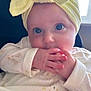 Flo is registered to the contest to win money with this photo: baby, infant, child, headband, yellow_bow, hands, fingers, sucking, white_outfit, duck_pattern, close_up, face, eyes, curious, sitting, chair, window, natural_light, indoor, portrait