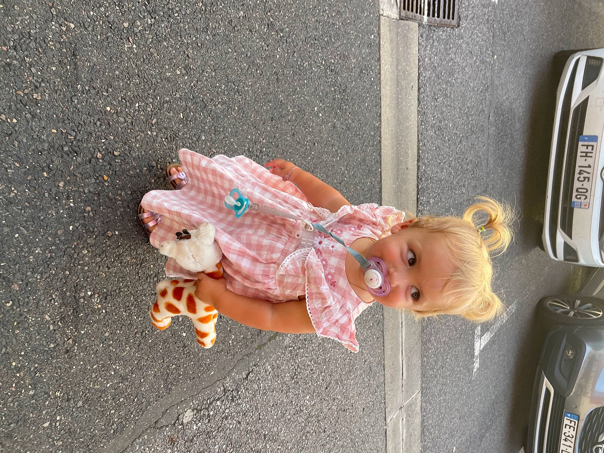 Leïa participe au concours pour gagner de l'argent avec cette photo : asphalt, automotive_exterior, automotive_lighting, car, child, concrete, doll, dress, family_car, fawn, fun, person, road, road_surface, sidewalk, sitting, toddler, toy, trunk, vehicle_door