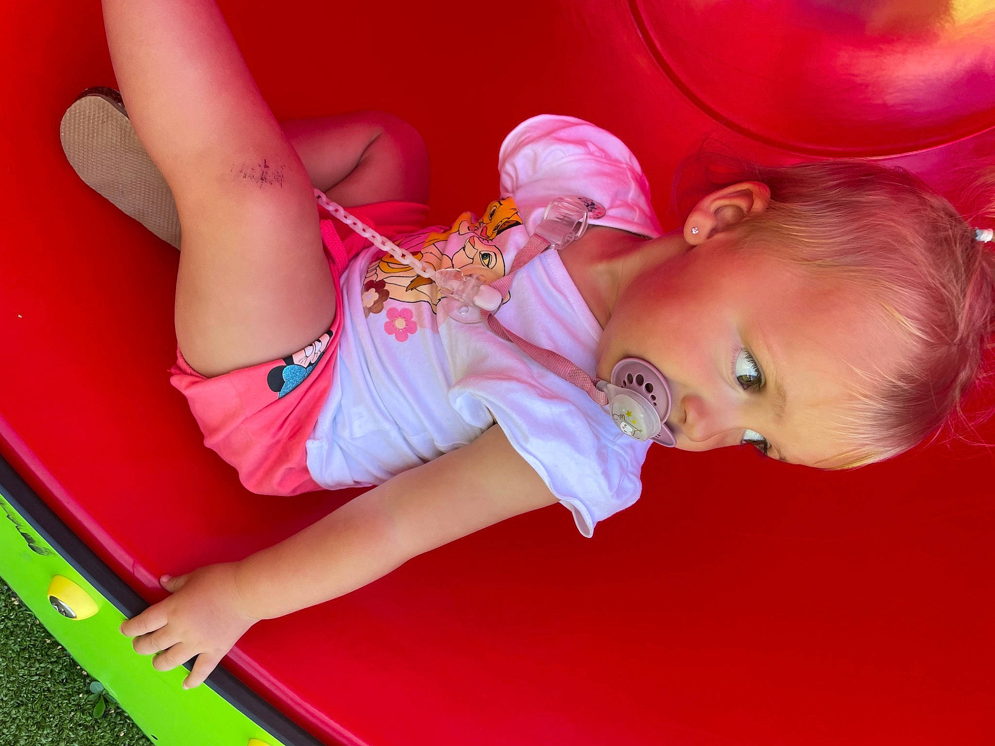 Leïa participe au concours pour gagner de l'argent avec cette photo : arm, baby, baby_products, baby_toddler_clothing, child, fun, happy, human_leg, leg, leisure, magenta, party, person, pink, play, red, room, sandal, sitting, thigh