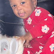 Amirerose is registered to the contest to win money with this photo: toddler, child, red_onesie, floral_pattern, smiling, tongue_out, curly_hair, earrings, black_leather_couch, indoor, playful, holding_object, toilet_paper, baby, person, cute, portrait, sitting, young_child, happy