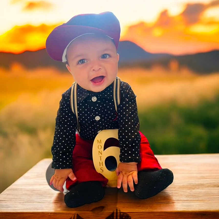 Marcelino joined the competition — help win amazing prizes! baby, baseballcap, cap, clothing, dress, face, grass, happy, hat, head, nature, outdoors, pants, person, photography, plant, portrait, sitting, sky, smile