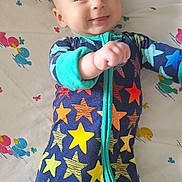 Gwen joined the competition — help win amazing prizes! baby, blanket, child, colorful_clothing, cute, duck_pattern, expression, face, hand, happy, indoors, infant, lying_down, onesie, playful, sleepwear, smiling, star_pattern, toddler, young