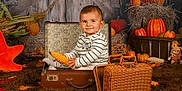 Tiago participe au concours pour gagner de l'argent avec cette photo : autumn, baby, brown_rug, child, corn, cozy, cute, decor, fall_leaves, hay, indoor, playful, portrait, pumpkin, seasonal, smile, striped_shirt, suitcase, vintage, wicker_basket