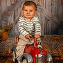 Tiago a rejoint le concours — aidez-le/la à gagner de superbes lots ! toddler, child, toy_car, indoor, autumn_leaves, smiling, striped_shirt, pants, brown_rug, wooden_background, playful, cute, small_vehicle, furniture, floor, hands, face, head, eyes, person