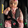 baby, child, car_seat, pink_bow, headband, pink_clothing, white_tights, safety_strap, infant, cute, indoor, seatbelt, serious_expression, toddler, portrait, baby_girl, sitting, closeup, child_seat, baby_fashion