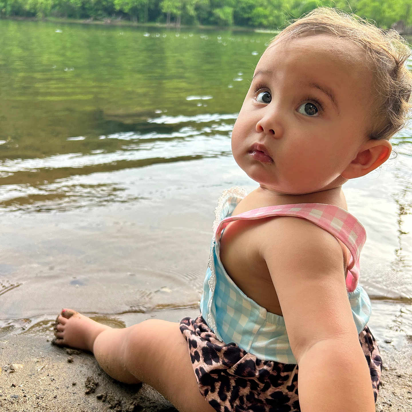 Irilynn joined the competition — help win amazing prizes! baby, checkered, child, clothing, curious, greenery, lake, leopard_print, nature, outdoor, peaceful, person, portrait, reflection, sand, sitting, summer, toddler, trees, water