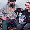 Zayden joined the competition — help win amazing prizes! family, baby, woman, man, dog, outdoor, water, log, clothing, hoodie, cap, glasses, pacifier, smile, beard, leash, nature, happy, sitting, swaddle