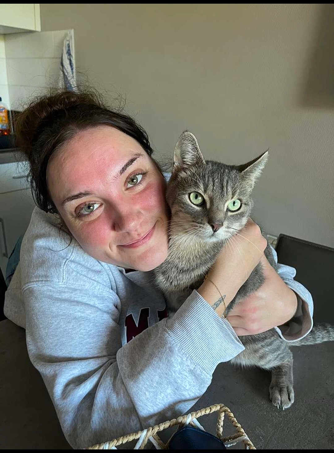 Sprygue participe au concours pour gagner de l'argent avec cette photo : basket, casual_clothing, cat, comfort, face, friendly, gray_cat, green_eyes, home, hug, indoor, kitchen, neutral_wall, pet, portrait, smile, tabby_cat, table, tattoo, woman