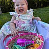 baby, bow, child, cute, dress, easter_basket, face, floral, girl, grass, grass_background, hand, happy, headband, outdoor, pink, plastic_eggs, playpen, sitting, smiling