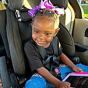 Miracle is registered to the contest to win money with this photo: child, girl, car_seat, graco, purple_bow, tablet, smile, sunlight, seatbelt, car_interior, happy, braided_hair, clothing, technology, sitting, daylight, window, vehicle, portrait, young_child