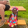 child, toddler, colorful_dress, hat, picnic_bench, barefoot, grass, outdoor, sunny, adult, legs, park, nature, summer, smiling, person, recreation, casual, fun, daytime