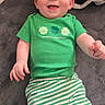 Cassius is registered to the contest to win money with this photo: baby, bed, blanket, clothing, cute, ears, eyes, face, green_color, green_shirt, hands, happy, holiday_shirt, infant, lying_down, portrait, smiling, st_patricks, striped_pants, toddler