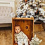 Rowan is registered to the contest to win money with this photo: baby, child, wooden_crate, pajamas, christmas_tree, holiday_decor, small_plant, wooden_floor, cozy, indoor, furniture, living_room, festive, pine_tree, snow_flocked, cute, seated, holiday, decoration, curious