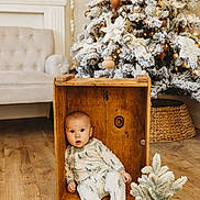 Rowan joined the competition — help win amazing prizes! baby, child, wooden_crate, pajamas, christmas_tree, holiday_decor, small_plant, wooden_floor, cozy, indoor, furniture, living_room, festive, pine_tree, snow_flocked, cute, seated, holiday, decoration, curious