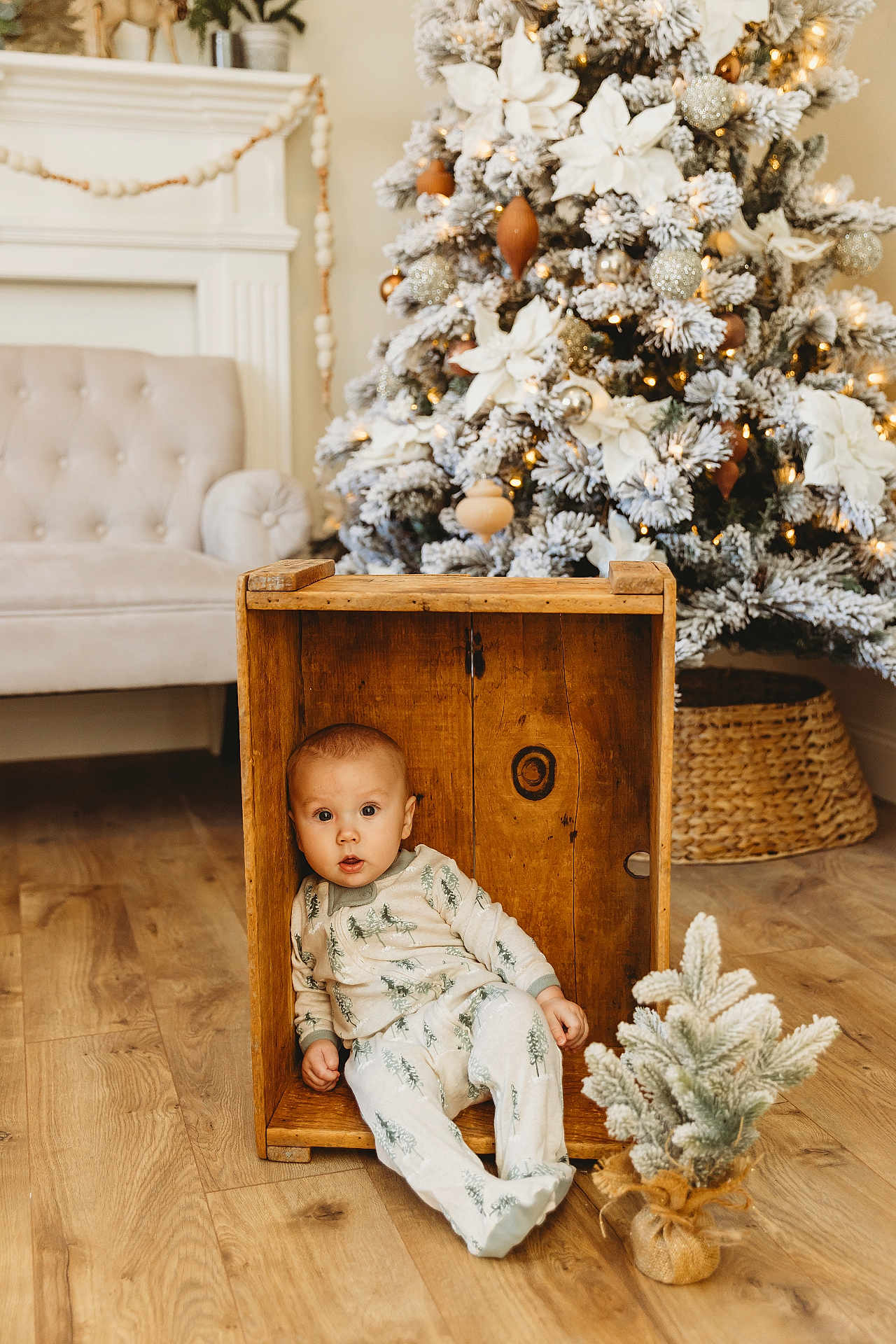 Rowan joined the competition — help win amazing prizes! baby, child, wooden_crate, pajamas, christmas_tree, holiday_decor, small_plant, wooden_floor, cozy, indoor, furniture, living_room, festive, pine_tree, snow_flocked, cute, seated, holiday, decoration, curious