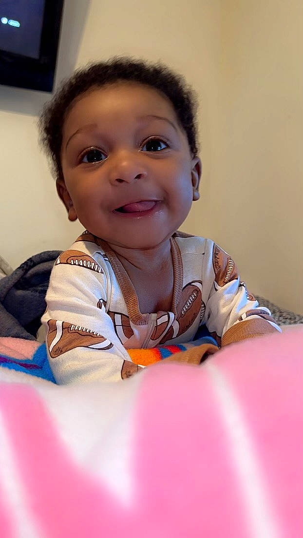 Josiah is registered to the contest to win money with this photo: baby, baby_toddler_clothing, cheek, child, comfort, eyebrow, face, finger, fun, happy, head, iris, mouth, nose, person, sitting, skin, sleeve, smile, t_shirt