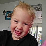 Gemma joined the competition — help win amazing prizes! toddler, child, smiling, tongue_out, blonde_hair, black_shirt, indoor, home, wall_art, cross, window, natural_light, happy, playful, portrait, face, person, cute, young_child, casual