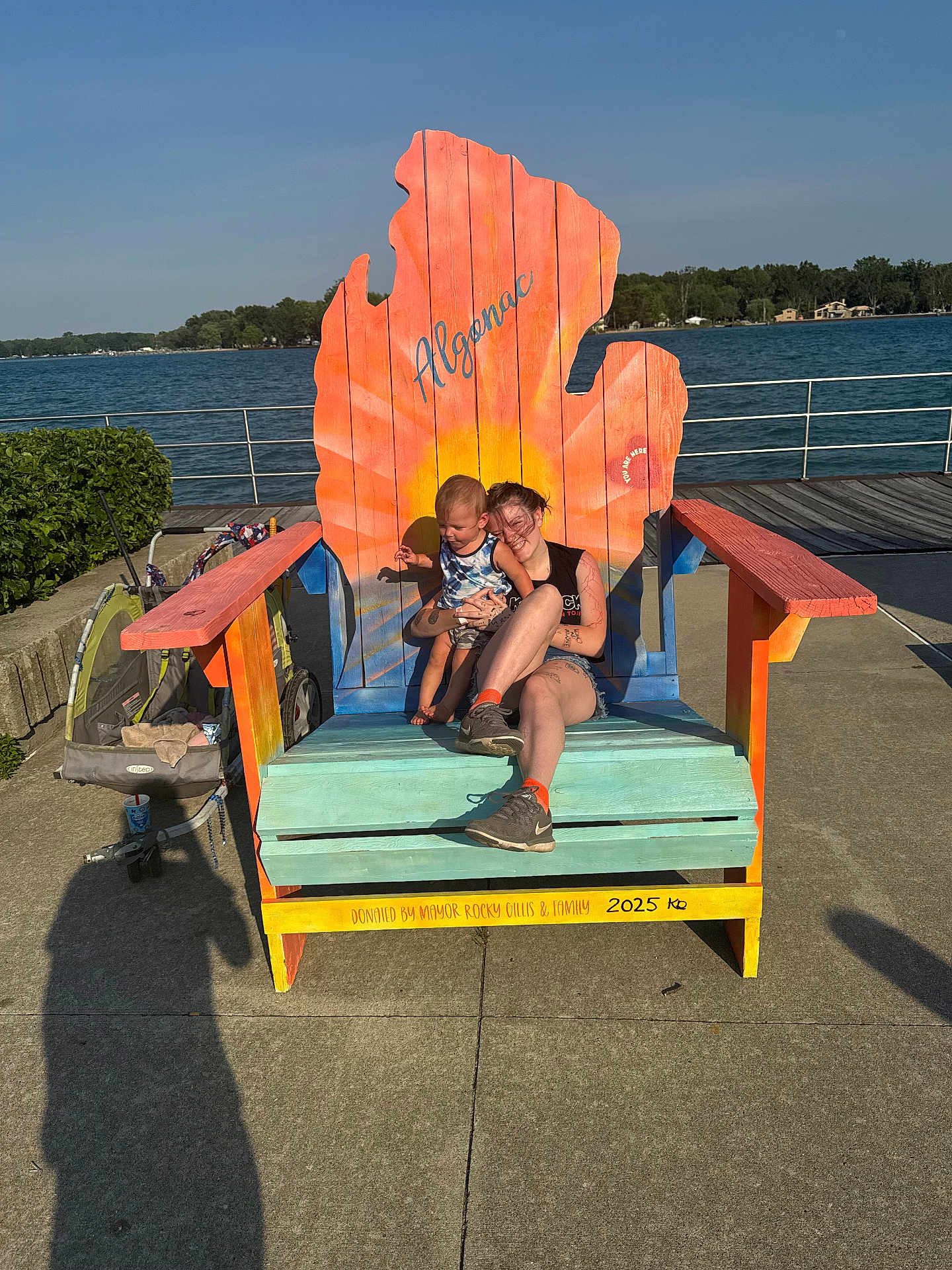 Keifton joined the competition — help win amazing prizes! child, woman, chair, outdoor, lake, water, sky, sunlight, stroller, concrete, trees, smile, casual_clothing, wood, colorful, shadow, daytime, nature, relaxation, people