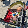 Lyniah-Dior joined the competition — help win amazing prizes! toddler, stroller, baby, child, red_blanket, american_flag, outdoor, sunlight, pavement, shadow, person, baby_bottle, seatbelt, footwear, mesh_pocket, toy, summer, transportation, family, daytime