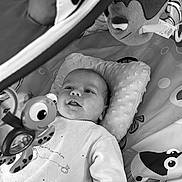 Jules a rejoint le concours — aidez-le/la à gagner de superbes lots ! baby, infant, toy, stuffed_animal, play_mat, pillow, smile, face, child, cute, lying_down, soft_toy, patterned_mat, black_and_white, indoors, happy, looking_up, clothing, infant_toys, baby_play