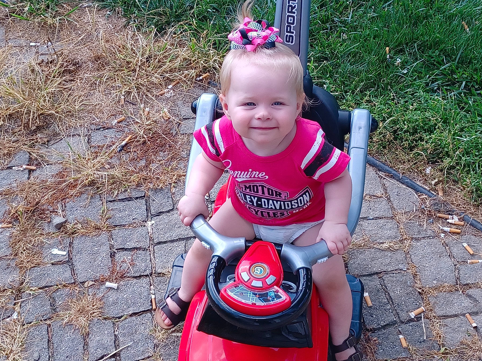 Gabriella is registered to the contest to win money with this photo: baby, baby_products, baby_toddler_clothing, child, eye, face, fun, grass, happy, head, joy, people_in_nature, person, personal_protective_equipment, pink, plant, recreation, smile, t_shirt, tire